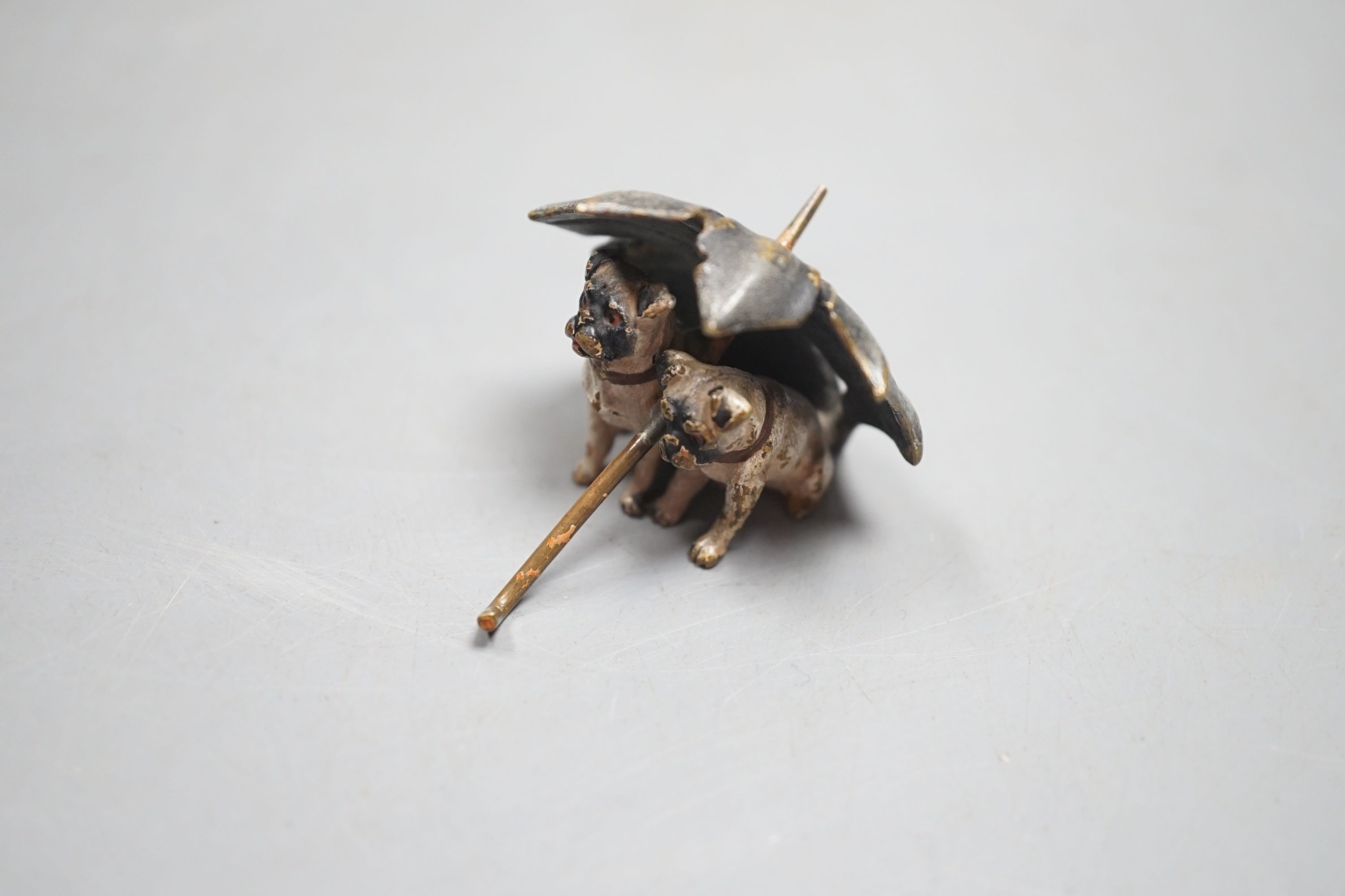 A small Austrian cold painted bronze group of two pug dogs under a rugged umbrella, 3cm